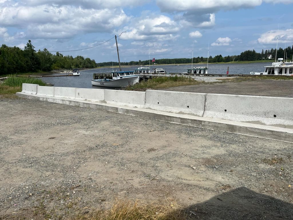 Plan large sur le quai de Bay-du-Vin, barricadé par des blocs de béton. Le port, visible à l'arrière-plan, semble toujours utilisé.