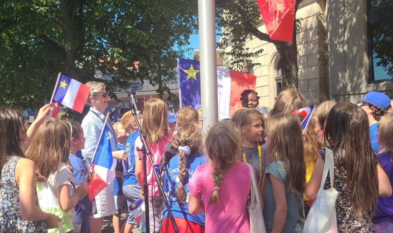 La mairesse de Saint-Jean, Donna Reardon est entourée d'enfants pour la levé du drapeau Acadien.