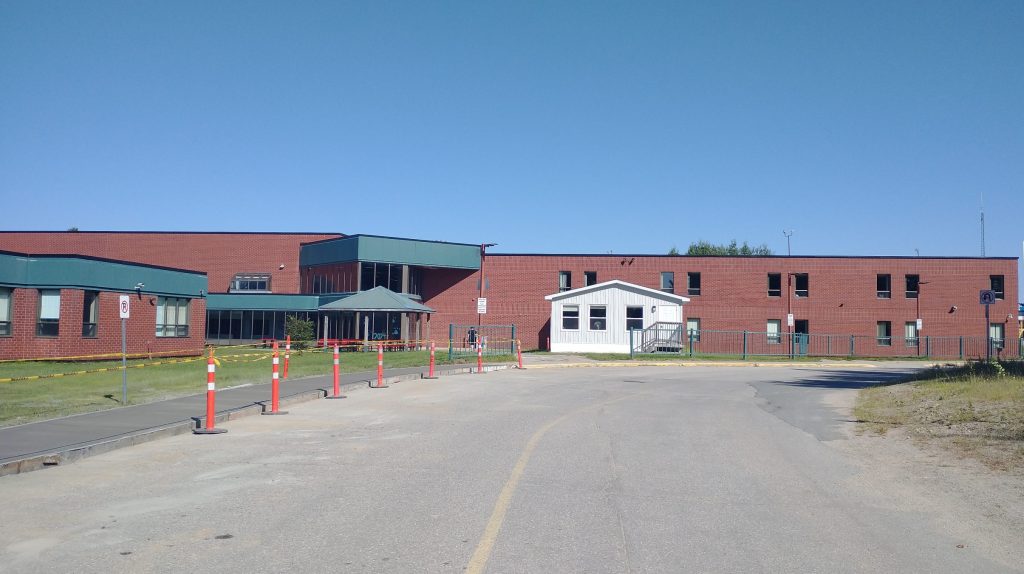 Plan large sur la façade de l'École Carrefour Beausoleil, avec un trottoir de béton fraîchement coulé.