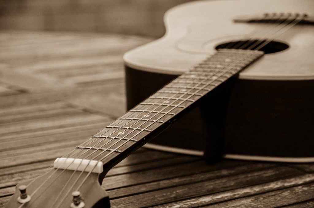 Plan rapproché d'une guitare posée sur le sol, en couleurs sépia.