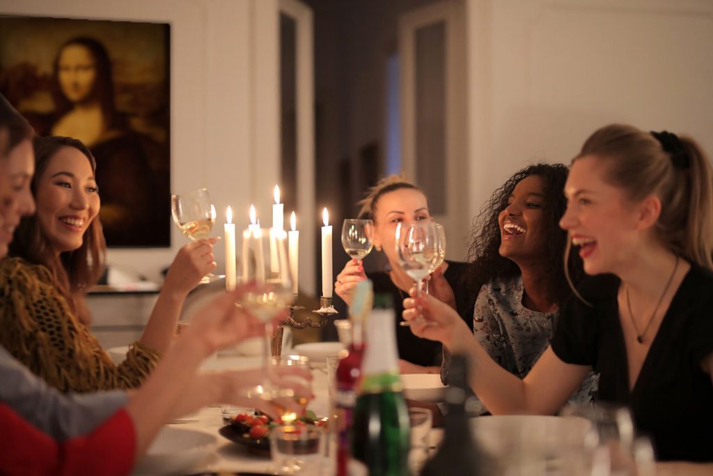 Des femmes sont réunies autour d'une table, dans un décor sobre illuminé aux chandelles.