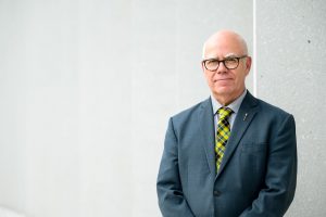 Photo de David Coon devant un mur de béton blanc.