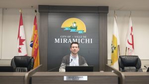 Le maire de Miramichi Adam Lordon est assis à sa place dans la salle du conseil municipal.