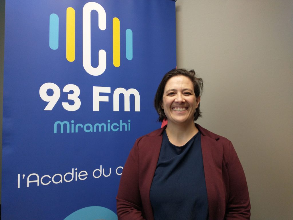 Bénédicte Donval pose aux côtés du logo C93 Miramichi.