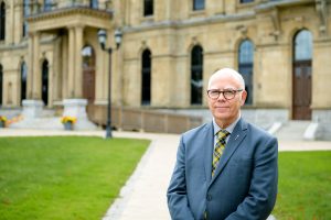 Photographie de David Coon devant le bâtiment de l'Assemblée législative du Nouveau-Brunswick, à Fredericton.