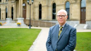 Photo de David Coon devant le bâtiment de l'Assemblée législative du Nouveau-Brunswick, à Fredericton.