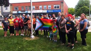 Photographie de groupe autour du drapeau de la fierté, au parc Reine Elizabeth de Miramichi.