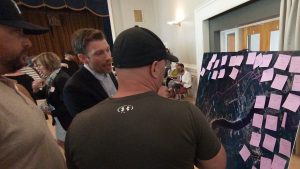 Photographie du maire de Miramichi Adam Lordon est en train d'expliquer un tracé à un petit groupe de personnes.