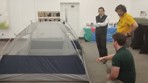Une personne du parc national de Fundy habillée en vert présente l'installation du'une tente de camping à des newcomers de Saint Jean