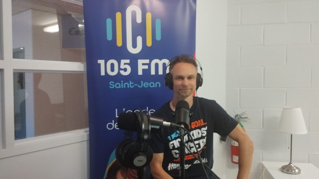 Jacques Desjardin, habillé d'un t-shirt de l'association SickKids est aux studios de la radio C105