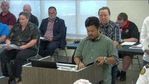 Capture d'écran montrant le directeur général de Sunfield properties Adan Aguilar en train de lire son rapport au conseil municipal.