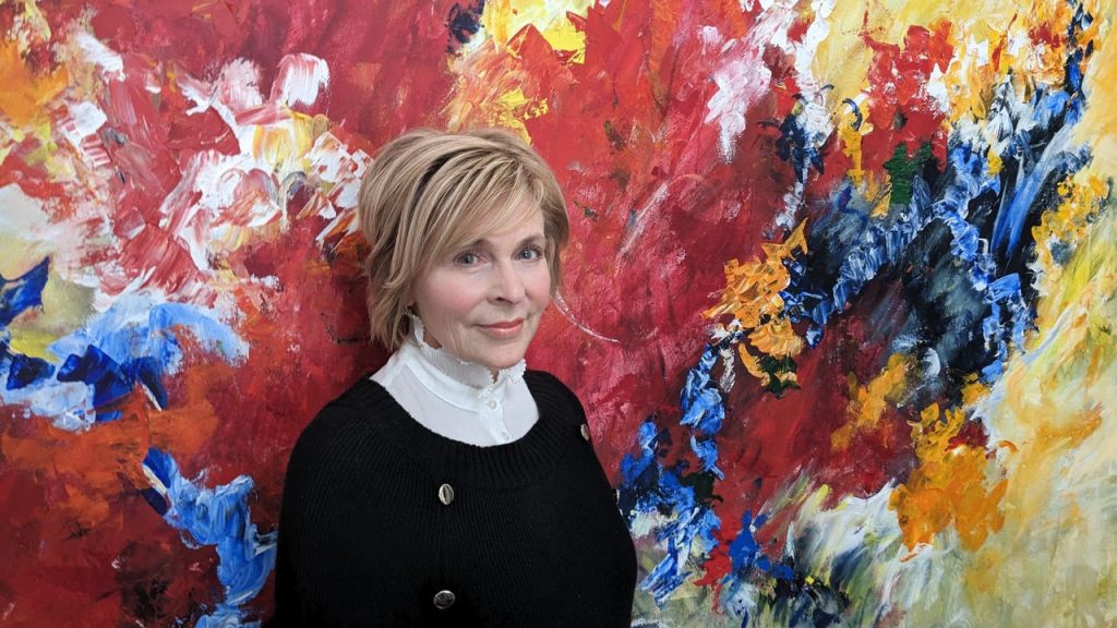 Photographie de Louise LeBlanc devant l'une de ses œuvres.