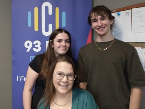 Photographie de Mélanie Sonier et deux élèves devant le logo de C93.