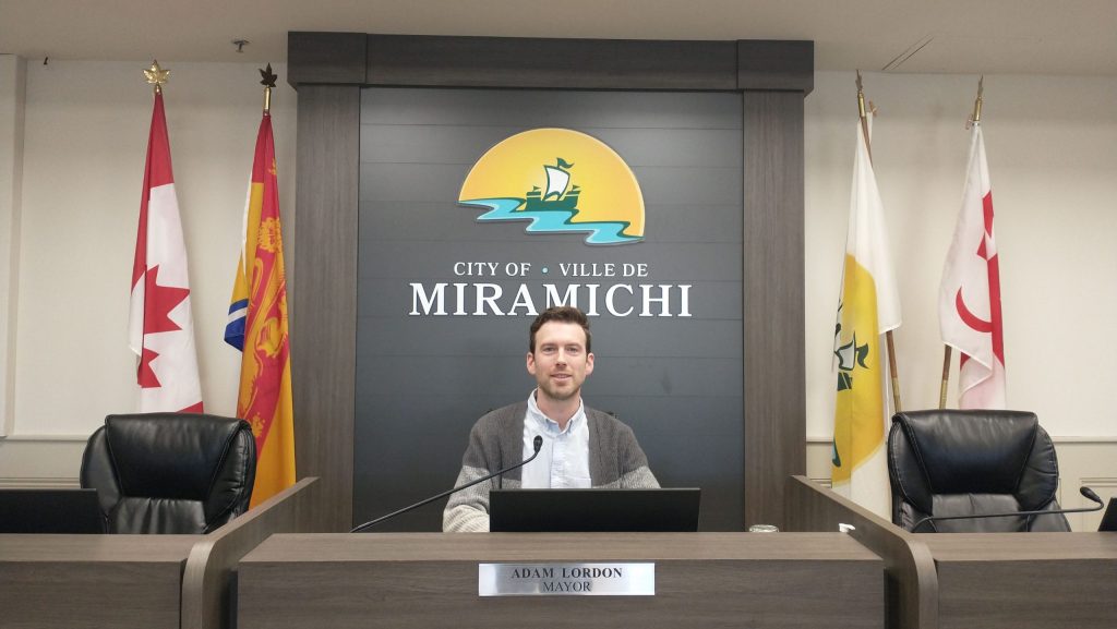 Le maire de Miramichi Adam Lordon est assis à sa place dans la salle du conseil municipal.