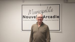 Photographie du maire de Nouvelle-Arcadie Jimmy Bourque devant une enseigne de la municipalité.