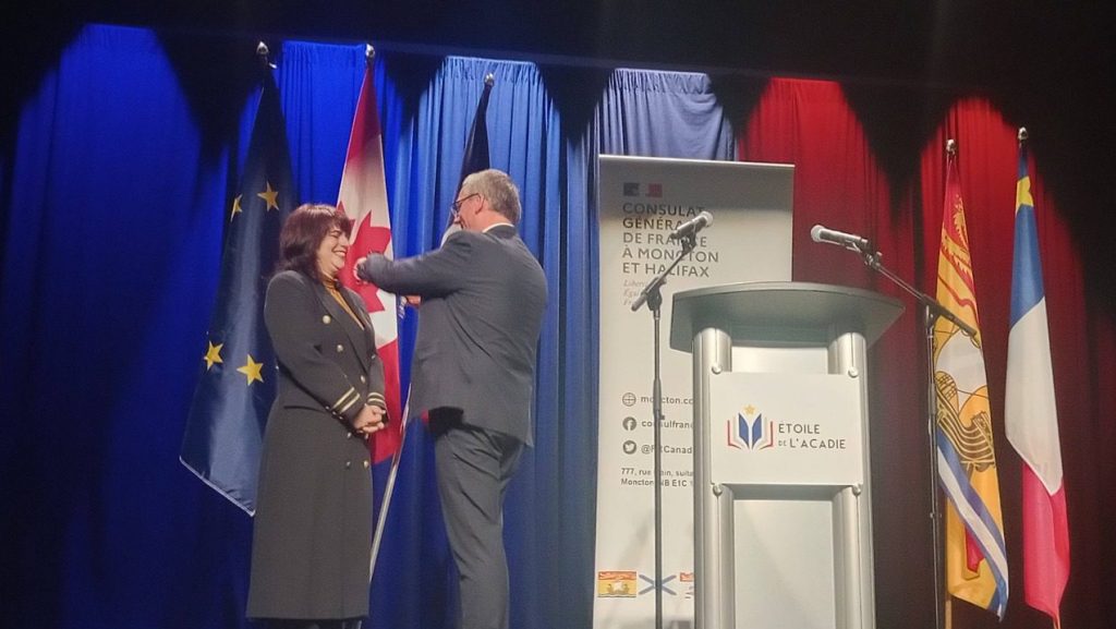 Photogrpahie de Lisa LeBlanc, souriante, en train de recevoir la distinction du consul de France.