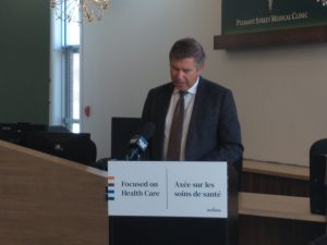 Photographie du ministre de la santé John Dornan en pleine allocution.