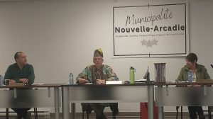 Photographie du maire, du directeur général et de la vice-mairesse de Nouvelle-Arcadie en pleine réunion du conseil municipal.