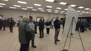 Plan large sur une salle de réception dans le centre d'expositions agricoles de Miramichi, remplie de gens et de kiosques informatifs.