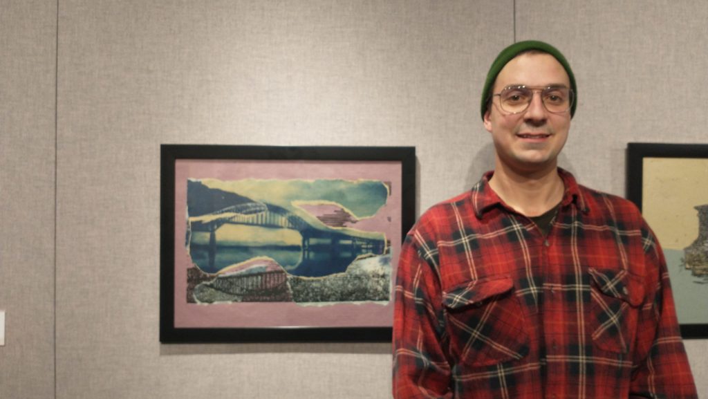 Photographie de Hugo Rioux qui pose aux côtés de l'une de ses œuvres.