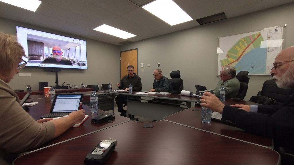 Photographie du conseil municipal de Neguac en pleine séance dans une salle de conférence.