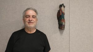 Photographie de Jean Allain aux côtés de l'une de ses oeuvres exposées à la gallerie ARTcadienne.