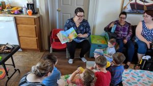 Photographie montrant une dame lisant une histoire à des enfants.