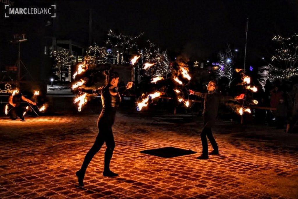 Photographie du trio Geomatrix en pleine prestation, avec divers équipements enflammés.