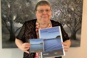 Photographie de Maria Léger tenant un exemplaire de son album et de son livret de chansons.