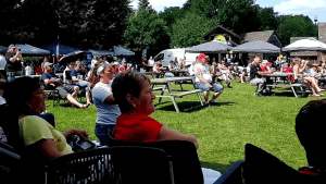 Photographie montrant un public nombreux assis à l'extérieur.