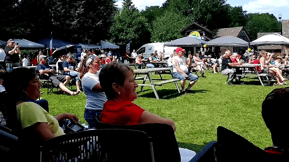 Photographie montrant un public nombreux assis à l'extérieur.