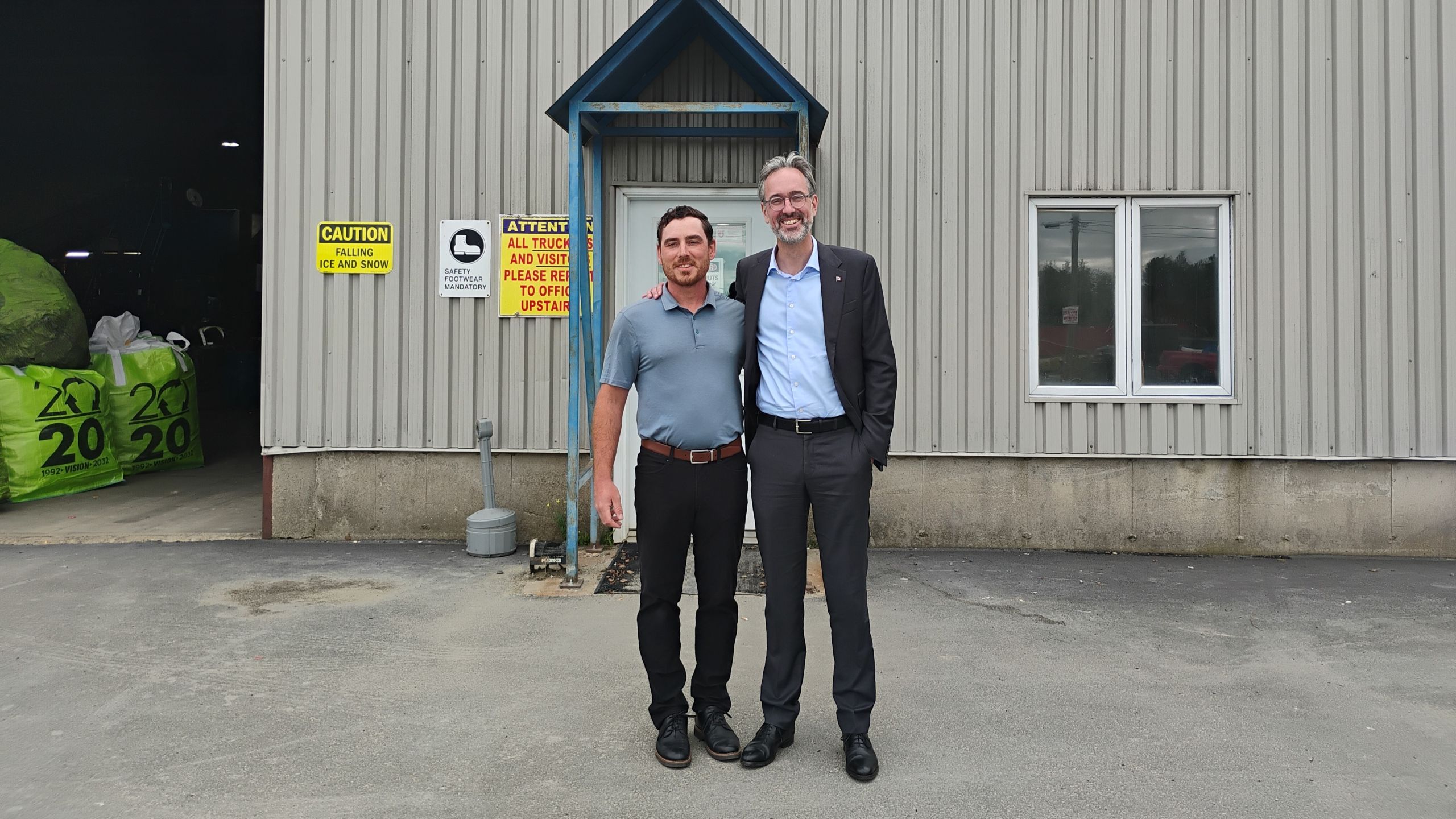 Photographie de David Myles et d'un chef d'entreprise devant une installation de recyclage.