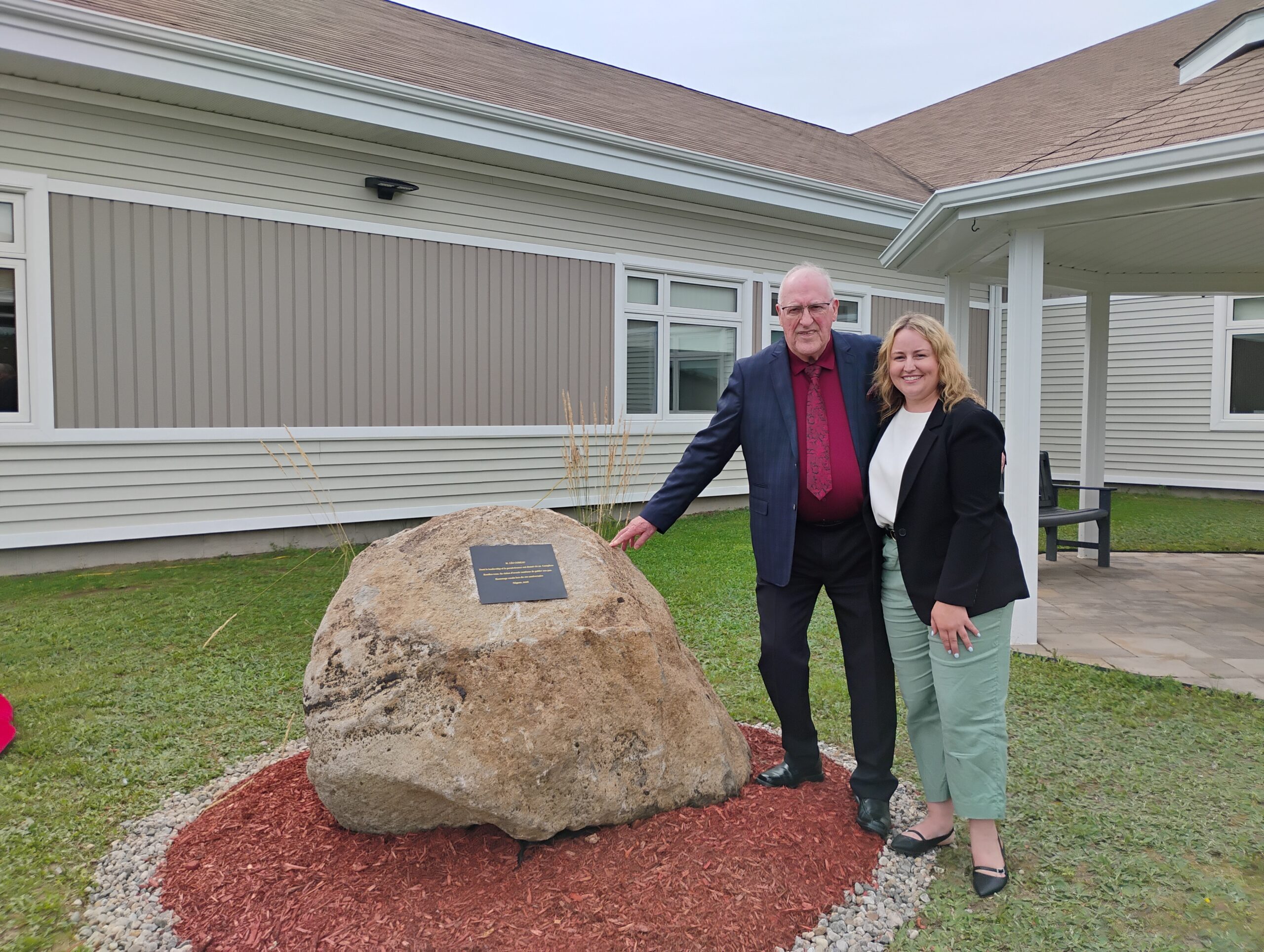 Photographie de Léo Comeau et Josée LeGresley aux côtés d'une plaque commémorative.