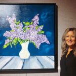 Photographie de Mélanie Gagnon aux côtés de l'une de ses œuvres, dans la Galerie ARTcadienne.
