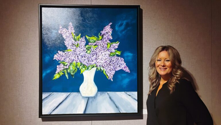 Photographie de Mélanie Gagnon aux côtés de l'une de ses œuvres, dans la Galerie ARTcadienne.