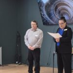 Photographie de Craig Silliker et Juliette Cabana aux côtés de bannières aux couleurs de l'Association régionale multiculturelle de Miramichi.