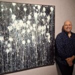 Photographie de Carl Philippe Gionet aux côtés de l'une de ses toiles dans la Galerie ARTcadienne.