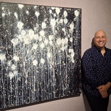 Photographie de Carl Philippe Gionet aux côtés de l'une de ses toiles dans la Galerie ARTcadienne.